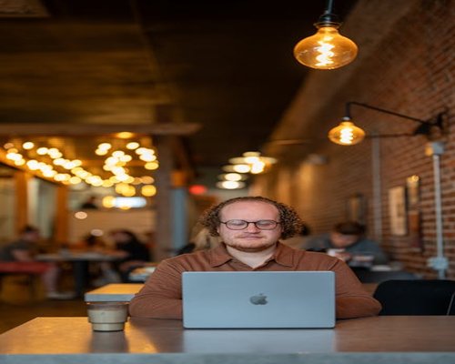Woman using laptop with glasses in a well lit cafe environment